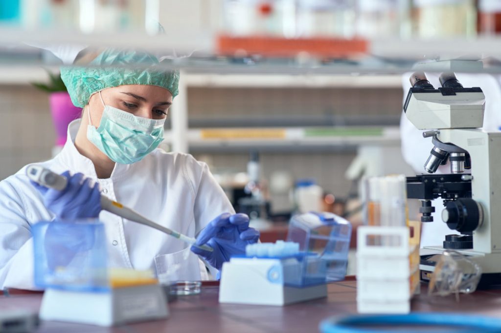 A scientist analysing a sample in a laboratory in protective clothing